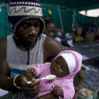 Un extranjero alimenta a su bebé en una tienda donde han sido realojados en Isibingo, en el sur de Durban, este lunes.