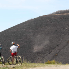 Dos ciclistas observan la montaña quemada por el fuego, el 21 de abril de 2017. ANA F. BARREDO
