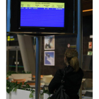 Pasajera ante la pantalla de vuelos del aeropuerto.