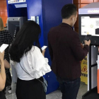 Personas hacen cola mientras utilizan sus teléfonos móviles, en Shanghái.