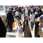 Dos niñas yemeníes pasean entre la gente por un mercado en la ciudad de Sanáa. Abajo, personas afectadas por la guerra hacen cola para recibir sus raciones de comida gratuitas de una organización caritativa local.