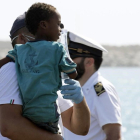 Un medico tiene en brazo un niño desembarcado del barco de la Guardia de Finanza en Pozzallo, Sicilia /