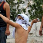 Un joven palestino lanza una piedra contra los antidisturbios israelíes en la Explanada de las Mezqu