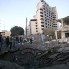 Varias personas observan el cráter que dejó la explosión de ayer en Bagdad.