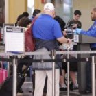 Un oficial de seguridad aeropuertaria revisa los documentos de viaje de los pasajeros.