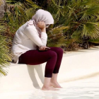 Una mujer musulmana, ataviada con un burkini, se refresca en una piscina