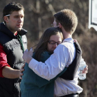 Varias personas se consuelan mutuamente en el exterior de la escuela Sandy Hook.