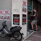 Colas ante cajeros en Atenas, con carteles a favor del 'no' en el referendum.