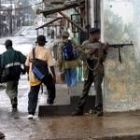 Un rebelde del LURD con su arma mientras varios niños circulan por las calles de Monrovia
