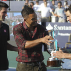 Nadal recibe de Will Smith, con Djokovic de espectador, el trofeo como ganador del partido.