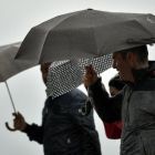 Unas personas se protegen de la lluvia.