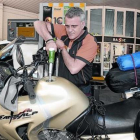 Un trabajador de una gasolinera llenando el depósito de una moto.