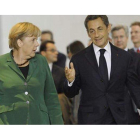 Angela Merkel y Nicolas Sarkozy se dirigen hacia la sala de conferencias tras mantener un primer encuentro en Berlín.