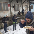 Refugiados comen en el exterior de un almacén abandonado en Belgrado.