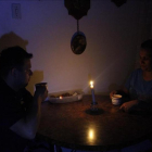 Una pareja toma un café en una establecimiento público a la luz de las velas.