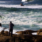 Un pescador lanza su caña sobre el mar picado en la playa de Santa María de Oia (Pontevedra). SALVADOR SAS