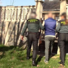 Dos agentes de la Guardia Civil con uno de los detenidos en una vivienda registrada. GUARDIA CIVIL