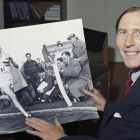 Roger Bannister, en una imagen de 1974, mostrando una foto de 20 años antes batiendo el récord de la milla.