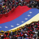 Seguidores del presidente Hugo Chávez extienden una bandera nacional gigante mientras esperan el paso del coche fúnebre.