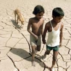 Dos niños indios caminan con su perro sobre un terreno agrietado por el calor