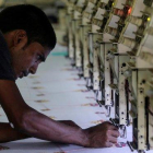 Un trabajador indio ajusta una máquina de coser en un planta de Bombai (India).