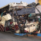 Una grúa remolca el autobús destrozado tras el impacto.