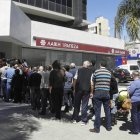 Varias personas hacen cola a las puertas de una sucursal de Laiki Bank en Chipre.