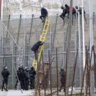 Varios de los inmigrantes encaramados en la valla.