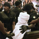 Habré, completamente tapado con una vestimenta blanca, rodeado de policías en el tribunal, en Dakar, este lunes.