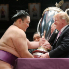 El presidente Donald Trump entrega una copa al ganador de un campeonato de sumo. JIJI PRESS