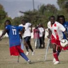 Varios hombres luchan por el balón en un partido para personas con amputaciones.
