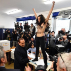 Una activista femenina protesta delante de Berlusconi cuando acudió a votar esta mañana