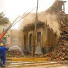 Un obrero arroja agua con una manguera durante la demolición