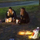 Unas jóvenes encienden velas en memoria de las víctimas del tiroteo en Burlington.