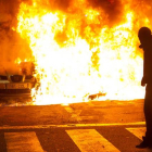 Un participante en los disturbios de Can Vies observa cómo arden los restos de un coche en la calle Sant Oleguer, el pasado 31 de mayo.