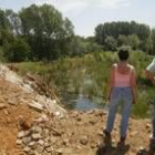 Dos vecinos contemplan el río donde una constructora arroja residuos