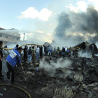 Un grupo de personas trabaja y busca pertenencias entre los escombros del mercado incendiado.