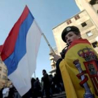 Un joven manifestante enarbola una bandera de Rusia mientras está envuelto en una bandera española