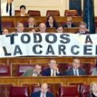 Los diputados de IU mostraron un cártel con la leyenda «Todos a la cárcel» durante la votación