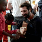 Un voluntario de Médico Sin Fronteras toca la guitarra junto a un niño