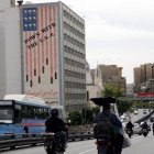Conductores iranís circulan junto a un edificio en el que aparece una pintada contra Estados Unidos en Teherán.