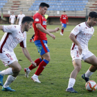 El jugador del filial leonés Rayan se lleva un balón bajo la atenta mirada de Abel MARCIANO PÉREZ