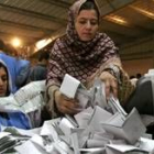 Dos mujeres mezclan las papeletas en el centro de recuento de Kabul