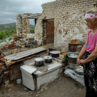 Una mujer cocina sobre los restos de su casa, destruida en el pueblo de Bohorodychne. OLEG PETRASYUK