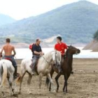 Los caballos descansan tras la carrera, con el pantano al fondo