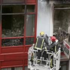 Unos bomberos retiran cascotes del inmueble incendiado