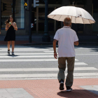 Un hombre se protege con un paraguas del sol que cae a plomo a primera hora de la tarde. LUIS TEJIDO