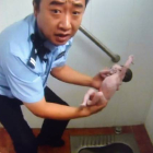 El policía, con la bebé en las manos, tras sacarla del urinario, el domingo en un local de Pekín.