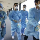 Varios médicos con mascarillas se dirigen a una puerta de llegada en el aeropuerto de Narita, al est