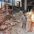 Dos menores juegan descalzos entre los escombros de una obra en un barrio de la capital india.